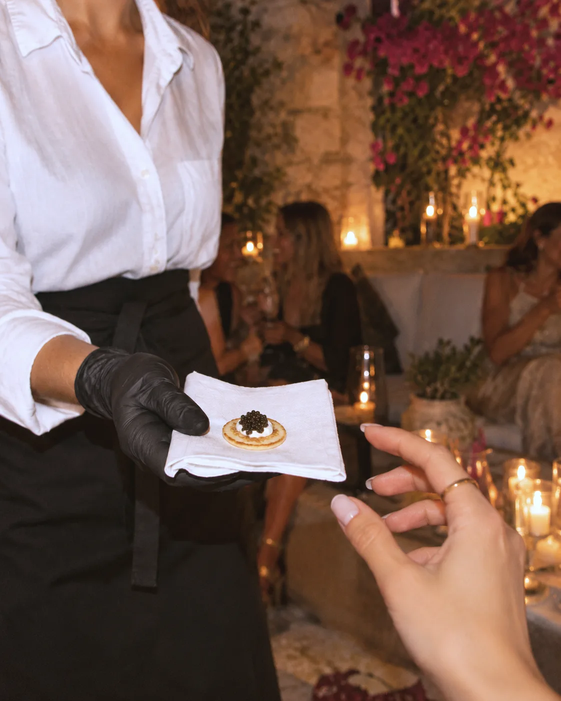 Caviar Passing: Ein Blini mit Kaviar wird einem Gast auf einer blühenden Terrasse auf Mallorca gereicht