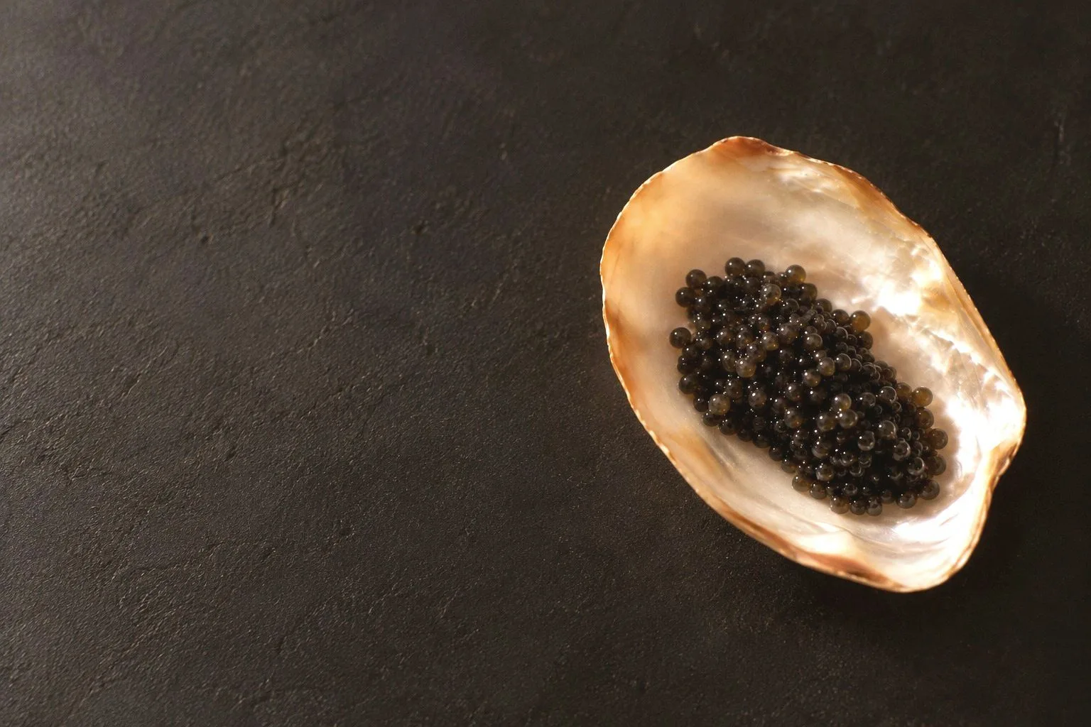 Caviar sur une coquille de nacre, sur fond charbon